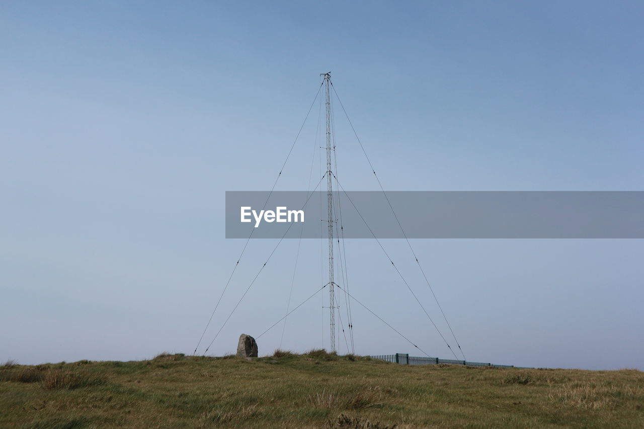 Low angle view of antenna in a green field and blue sky background