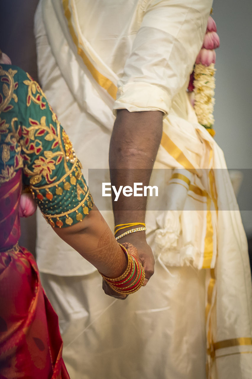 Midsection of couple holding hands during wedding