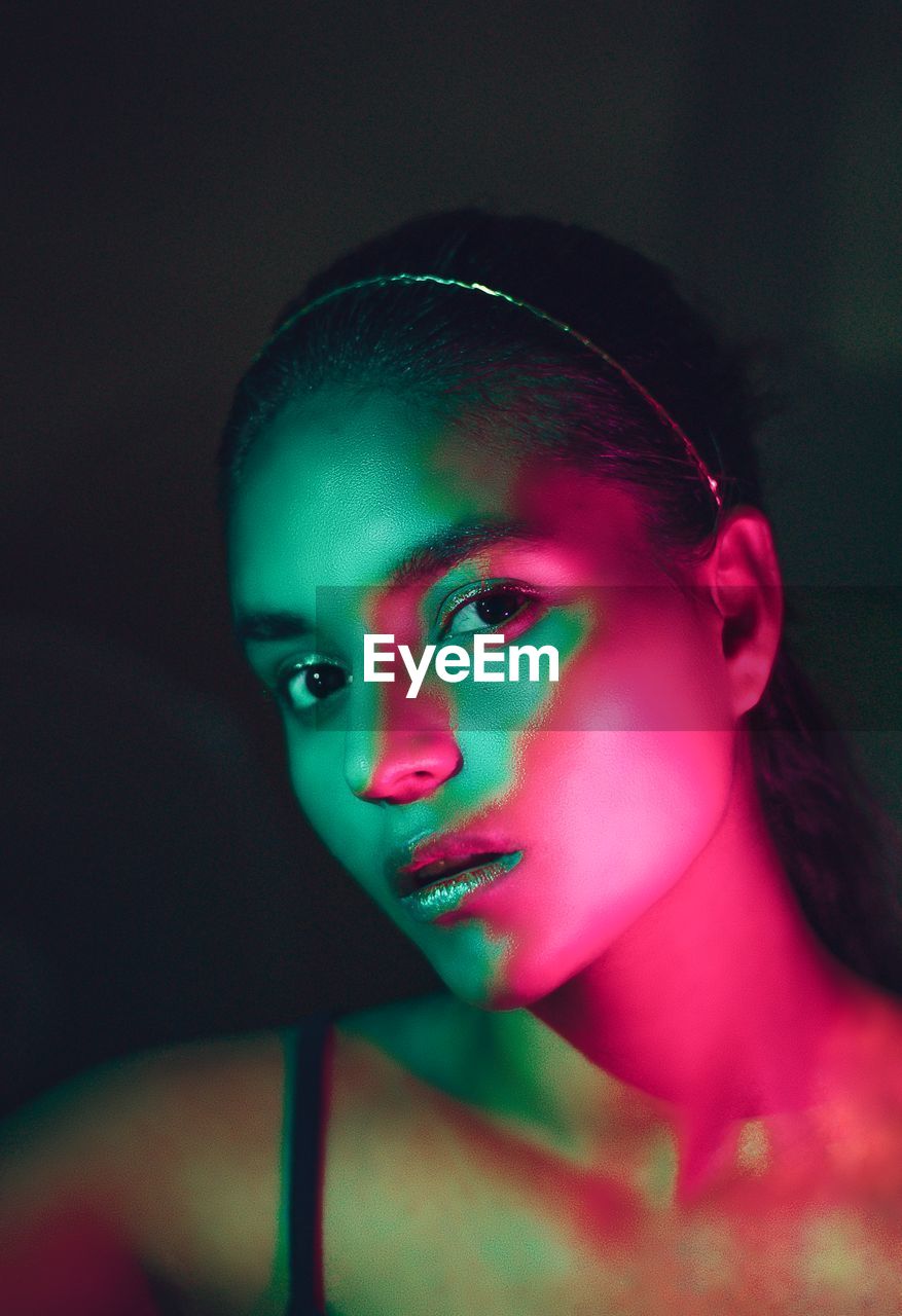 Close-up portrait of young woman against black background