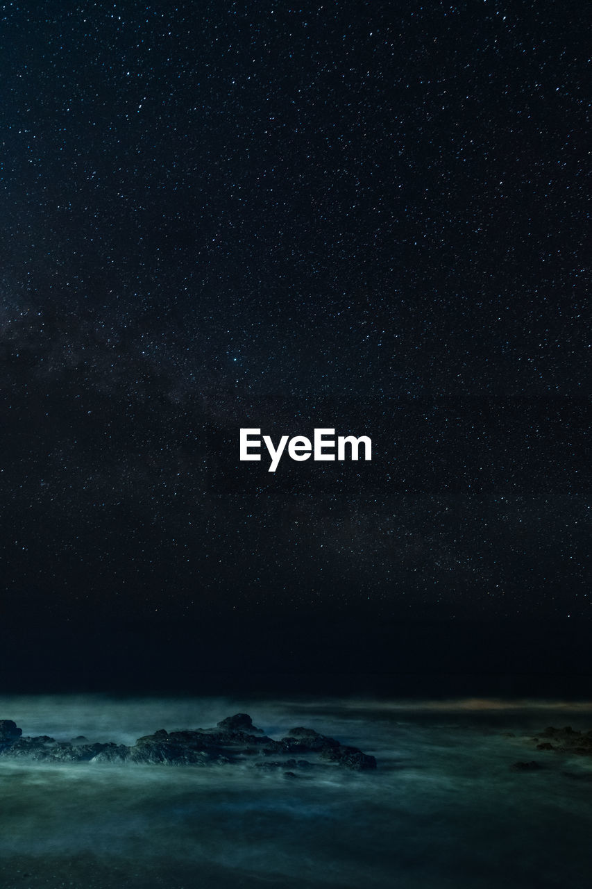 Long exposure of scenic view of sea against starry sky at night