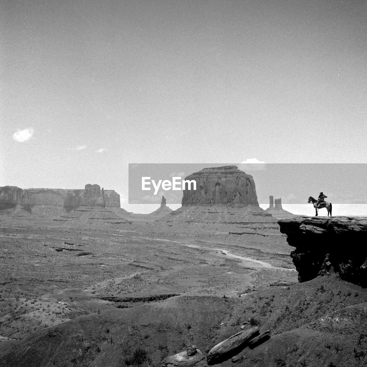 Man riding horse by rock formation against sky