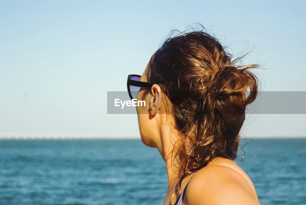 Portrait of young woman at beach against sky