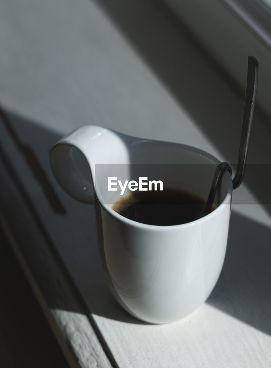 HIGH ANGLE VIEW OF COFFEE CUP AND SPOON ON TABLE