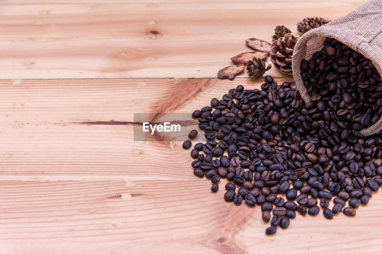 High angle view of roasted coffee beans with pine cones on wooden table