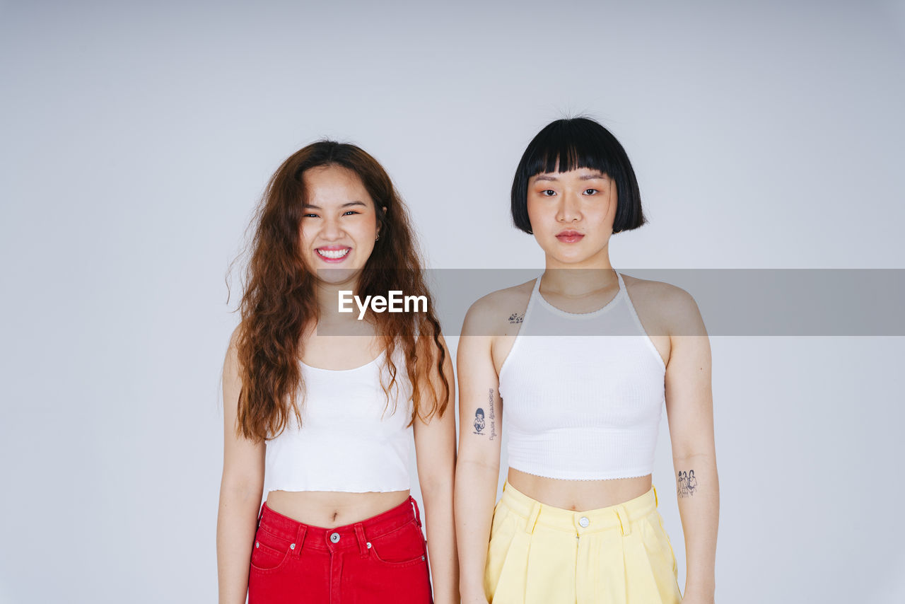 Portrait of smiling lesbian couple against gray background