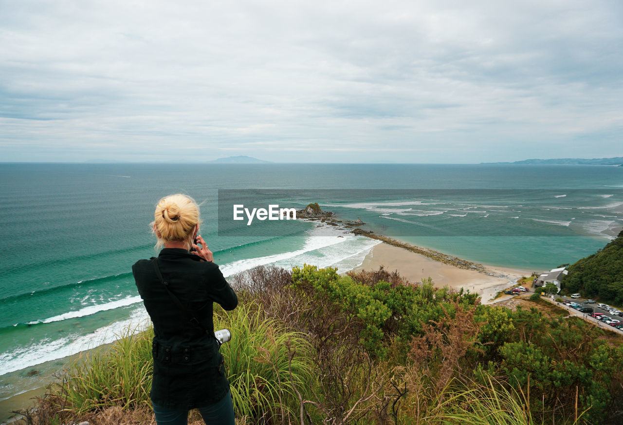 A woman hikes at mangawhai heads reserve in northland, new zealand.