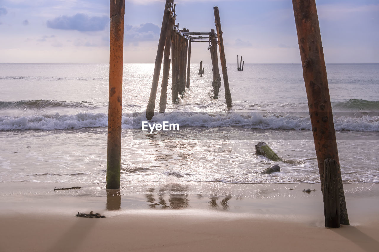 Wooden posts on beach against sky