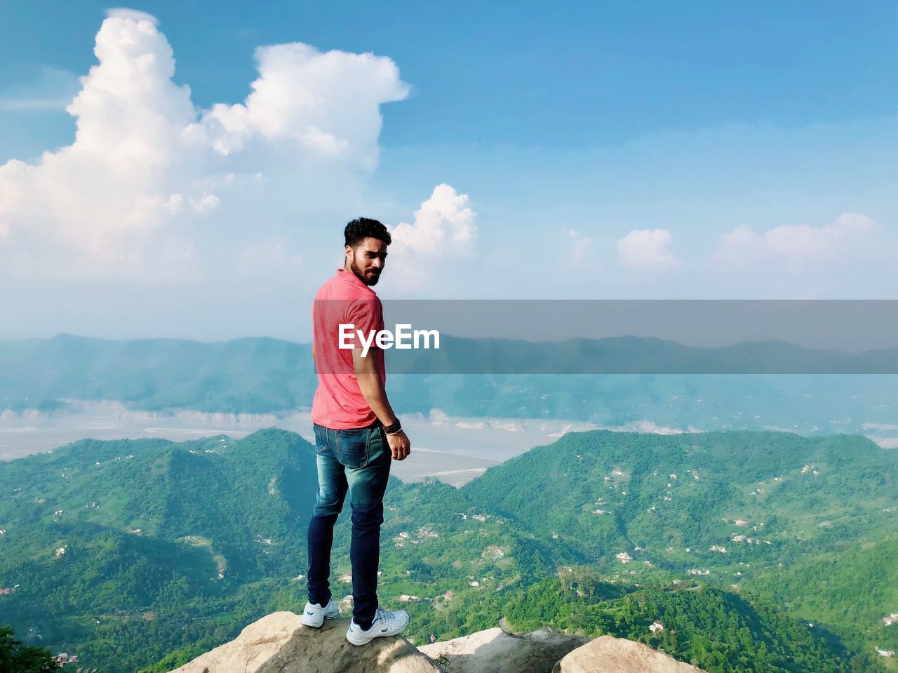 MAN STANDING ON MOUNTAIN AGAINST SKY