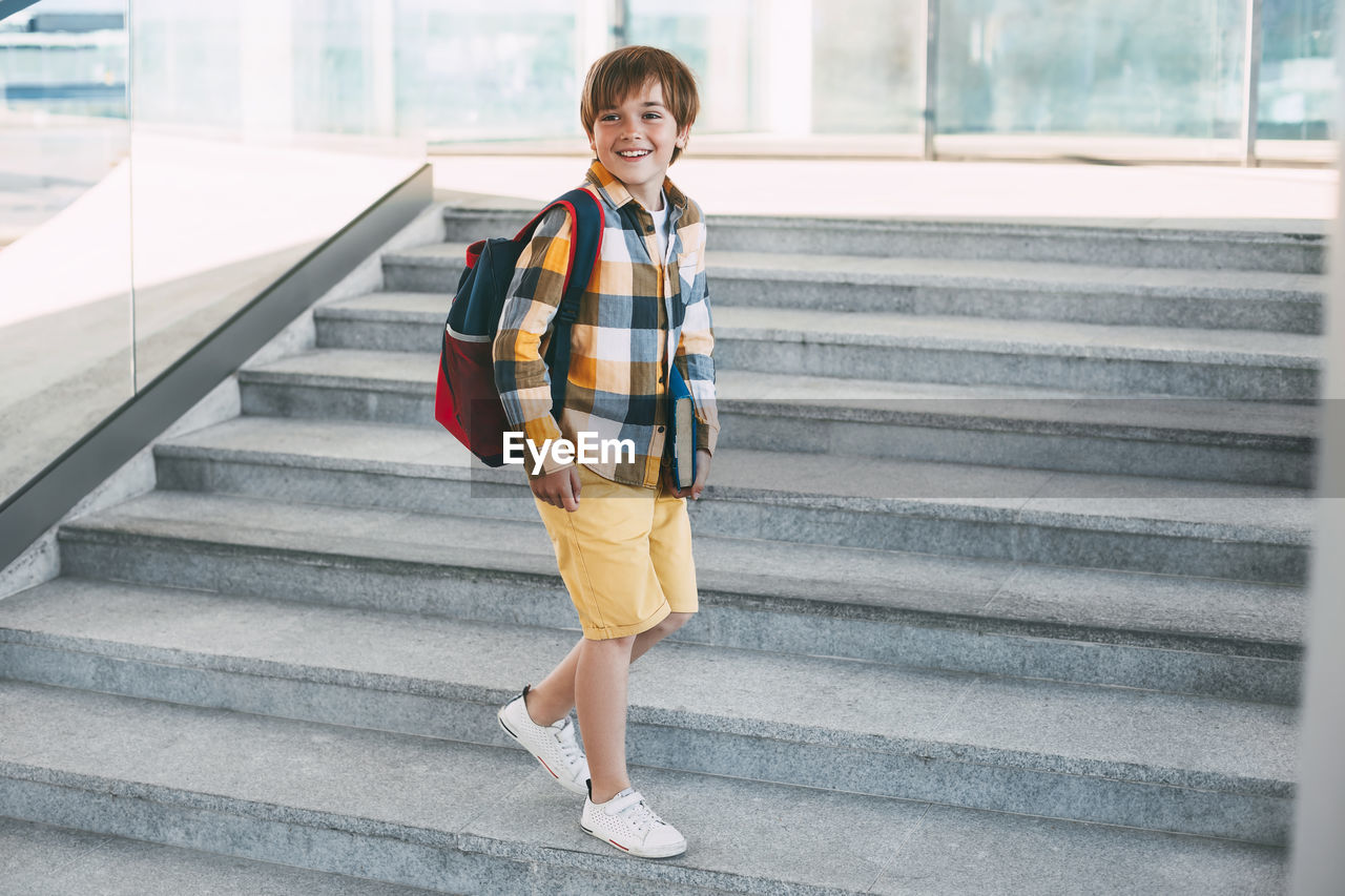 Boy looking away while standing on staircase