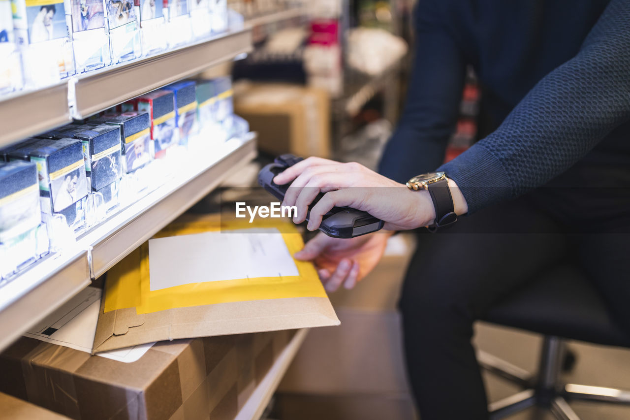 Male entrepreneur using bar code reader while analyzing package in store