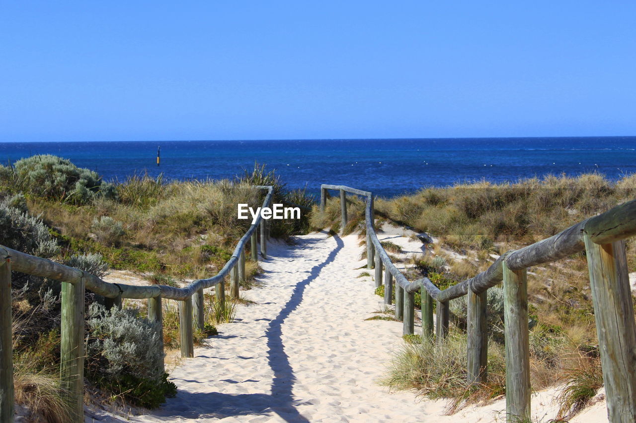 Railing at beach against sky