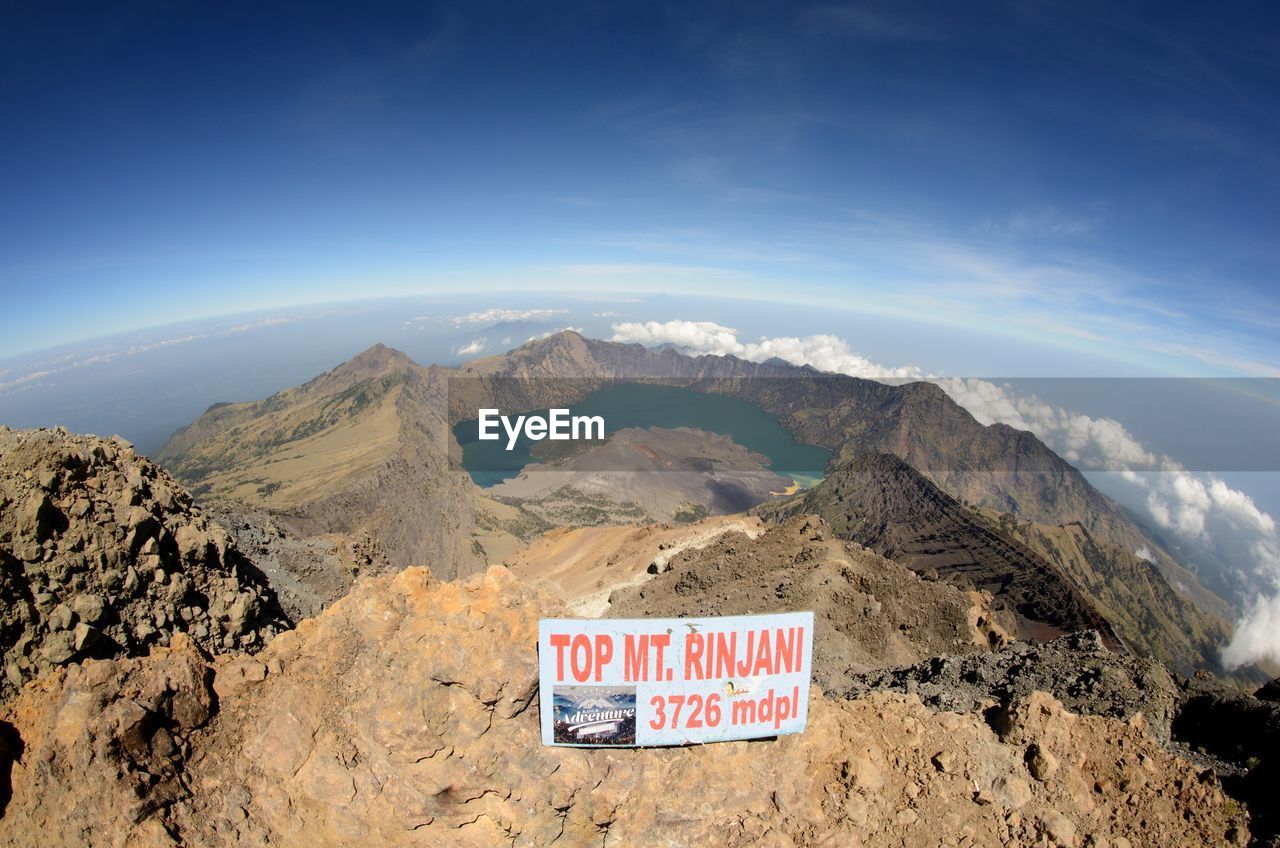 INFORMATION SIGN ON ROCKS AGAINST MOUNTAIN RANGE