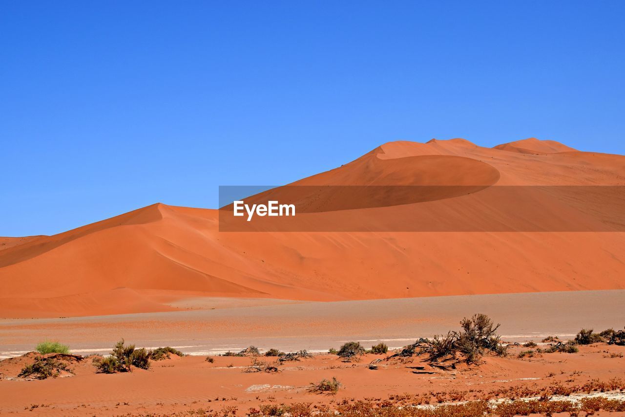 Scenic view of desert against clear blue sky