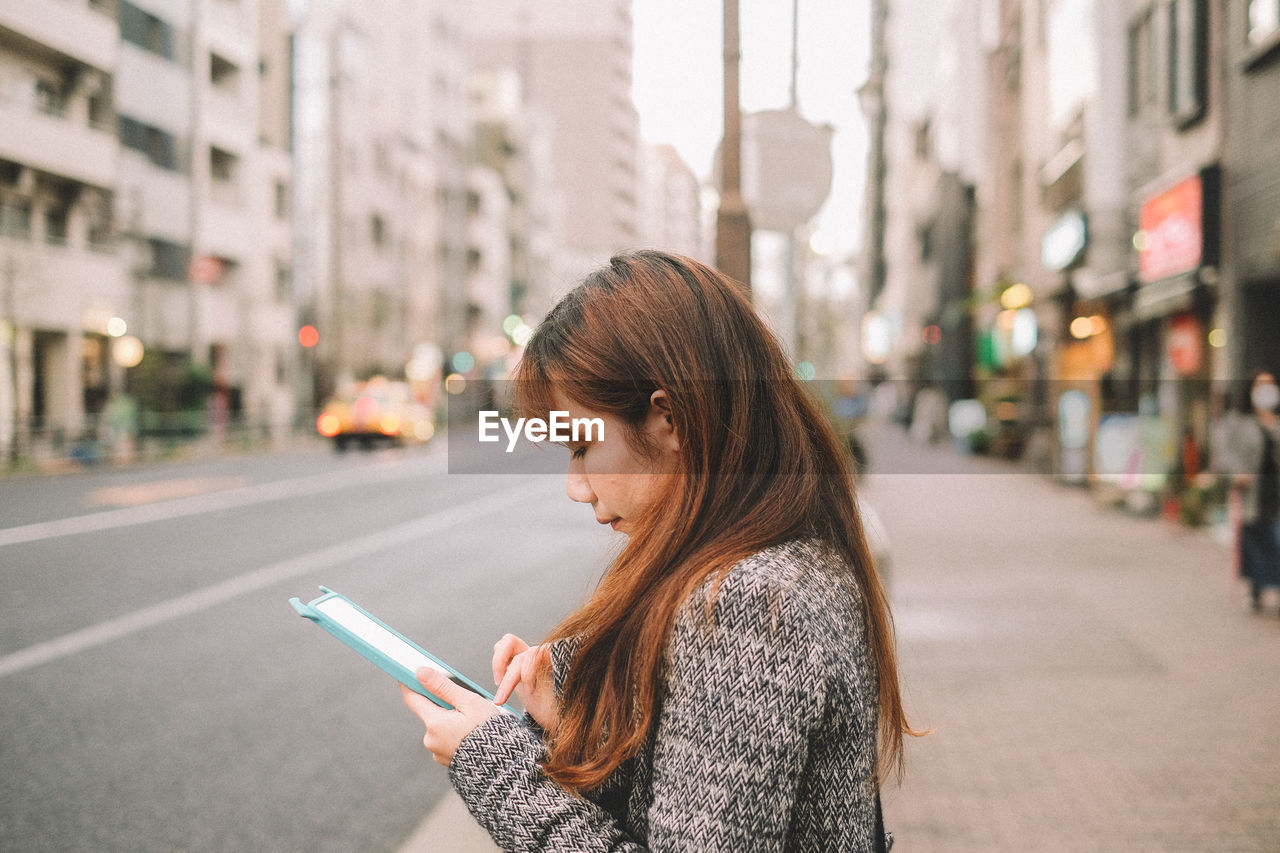 Woman using digital tablet in city