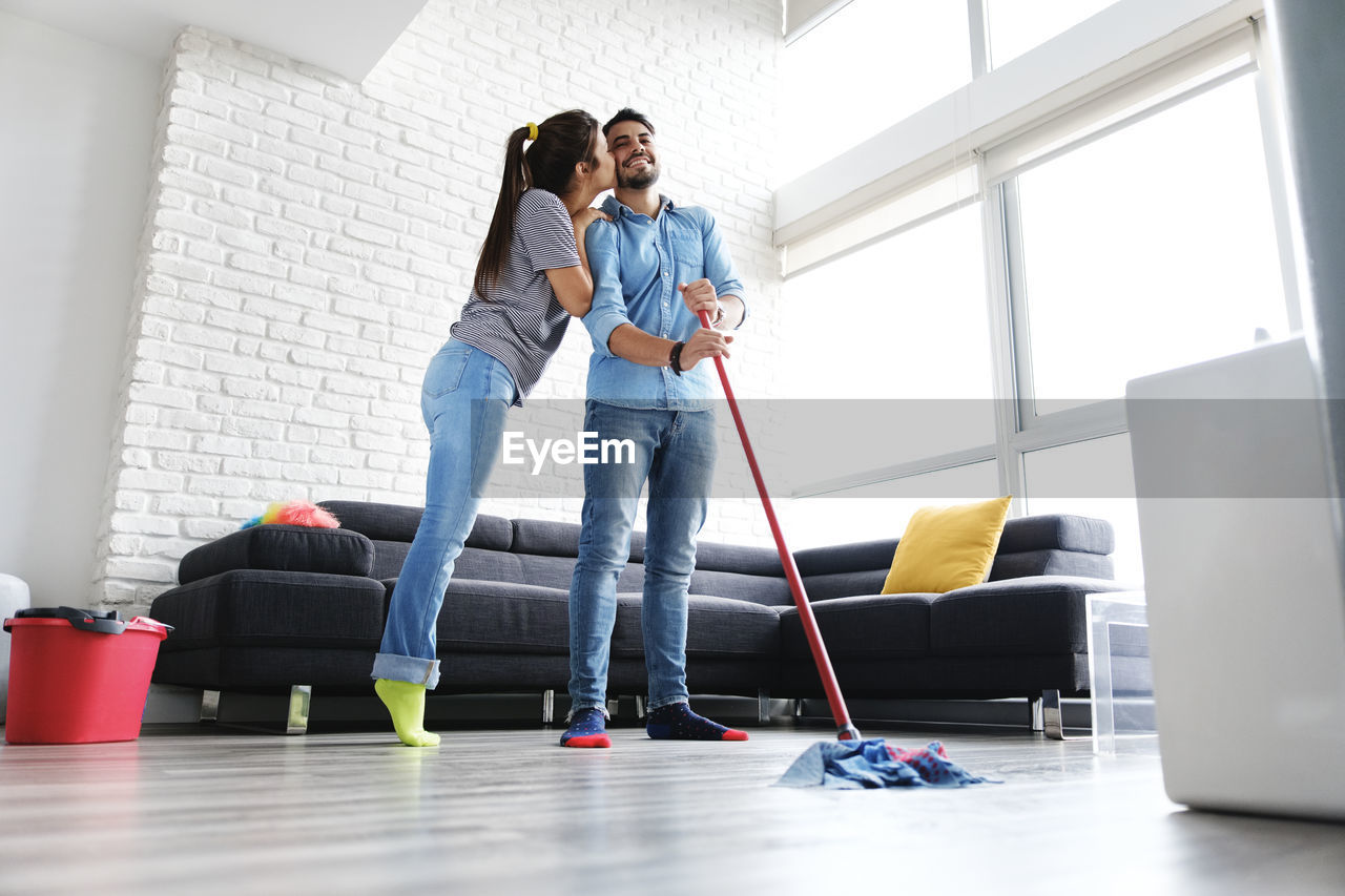 Woman kissing man cleaning floor at home