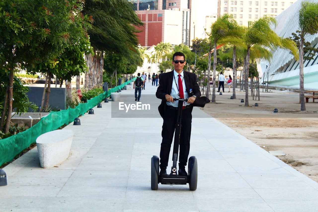 Businessman riding segway on footpath