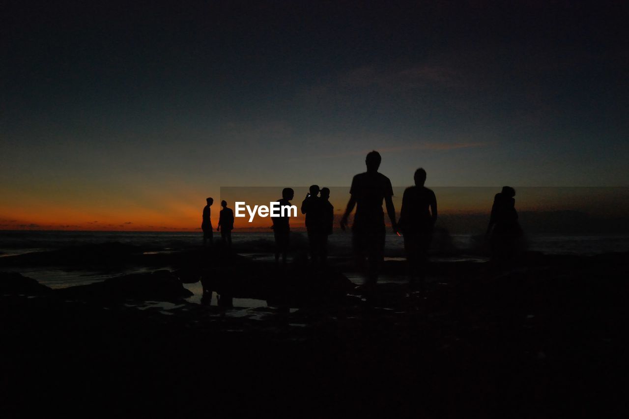 SILHOUETTE OF PEOPLE ON BEACH AT SUNSET