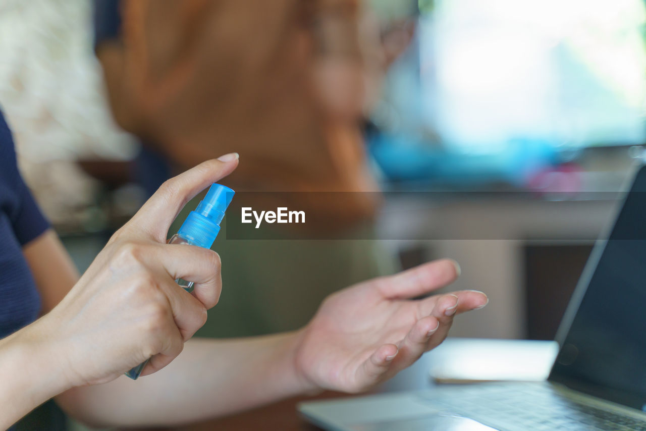 CLOSE-UP OF WOMAN HAND USING MOBILE PHONE IN LAPTOP