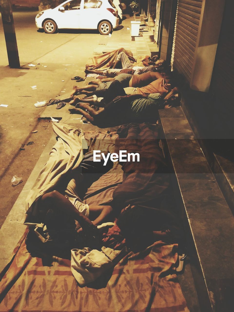 High angle view of people sleeping on footpath in city at night