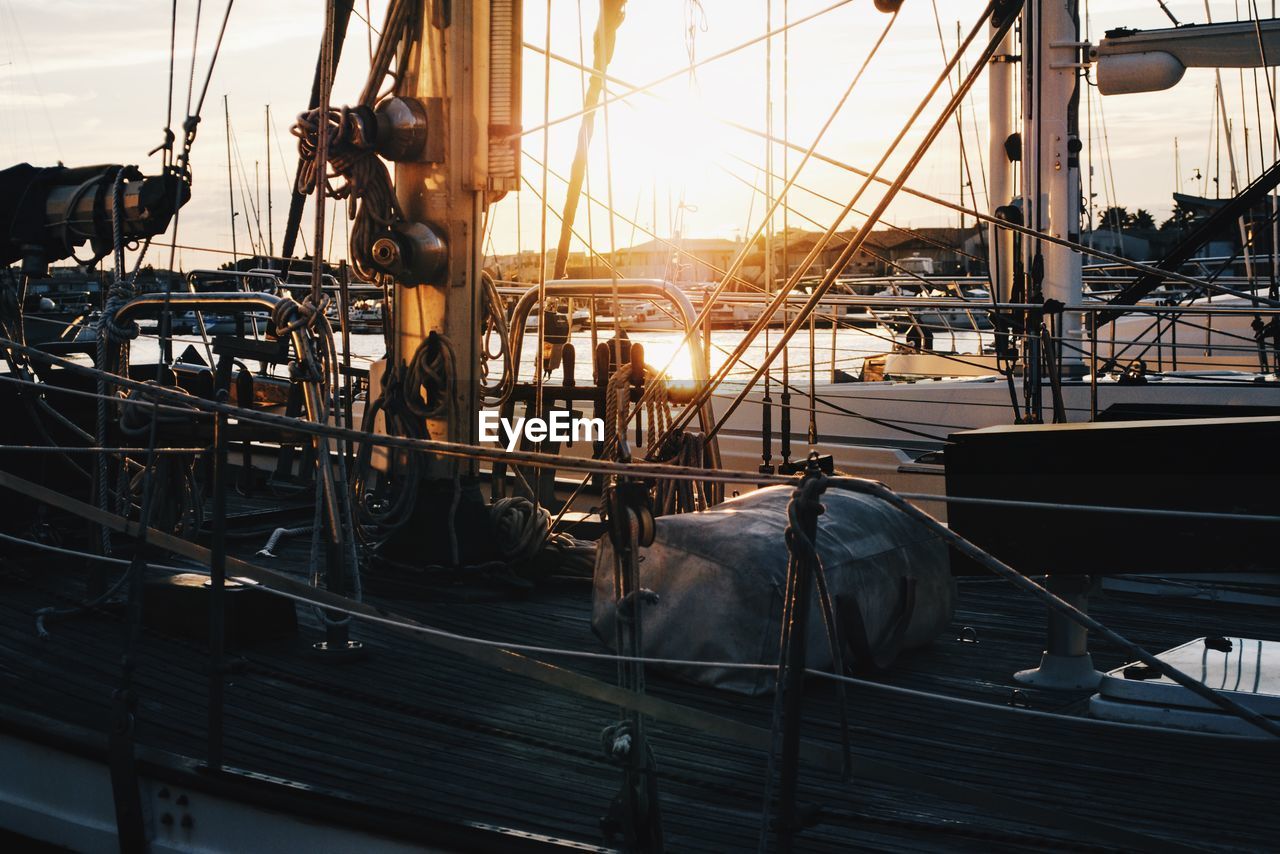 Boat moored at harbor during sunset