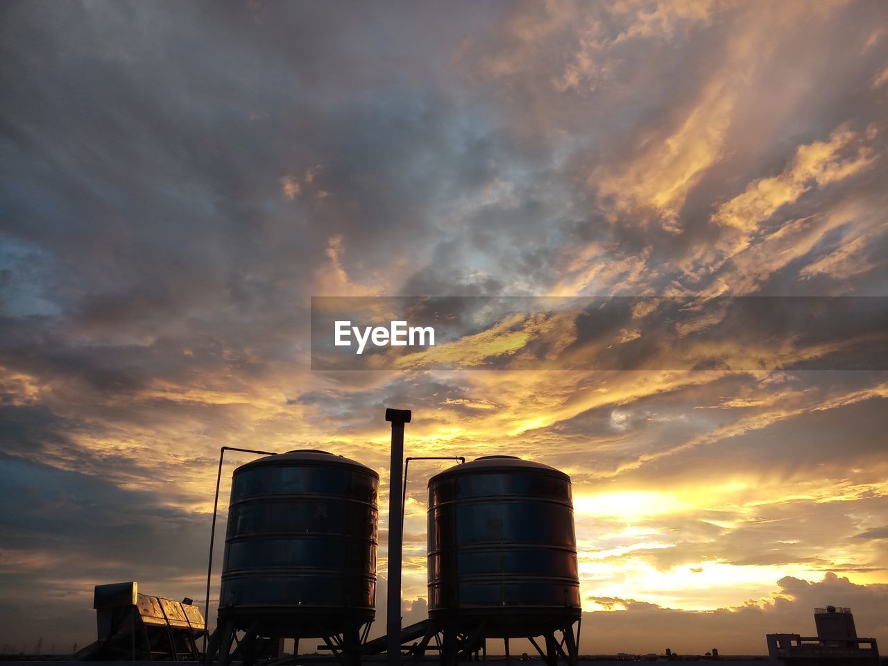 Low angle view of factory against sky during sunset