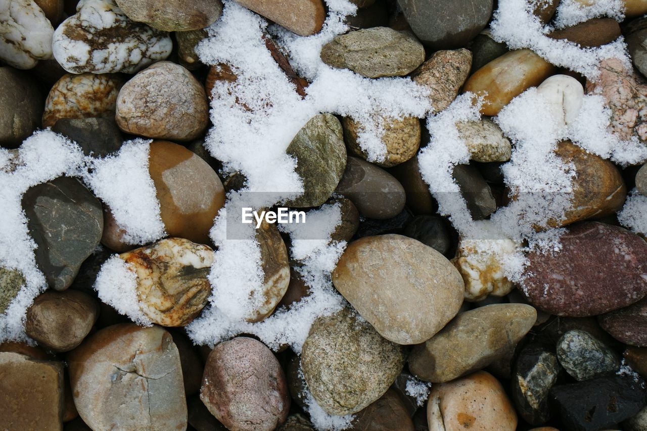 Full frame shot of snow on pebbles
