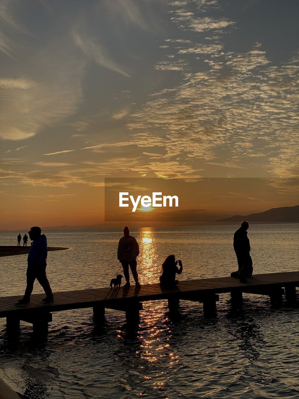 water, sky, sunset, sea, silhouette, horizon, nature, ocean, group of people, evening, reflection, dusk, beauty in nature, cloud, beach, men, scenics - nature, leisure activity, shore, land, sunlight, adult, holiday, wave, trip, lifestyles, vacation, sun, outdoors, horizon over water, tranquility, women, nautical vessel, transportation, coast, pier, togetherness, travel, travel destinations, idyllic, tranquil scene, orange color, summer, group