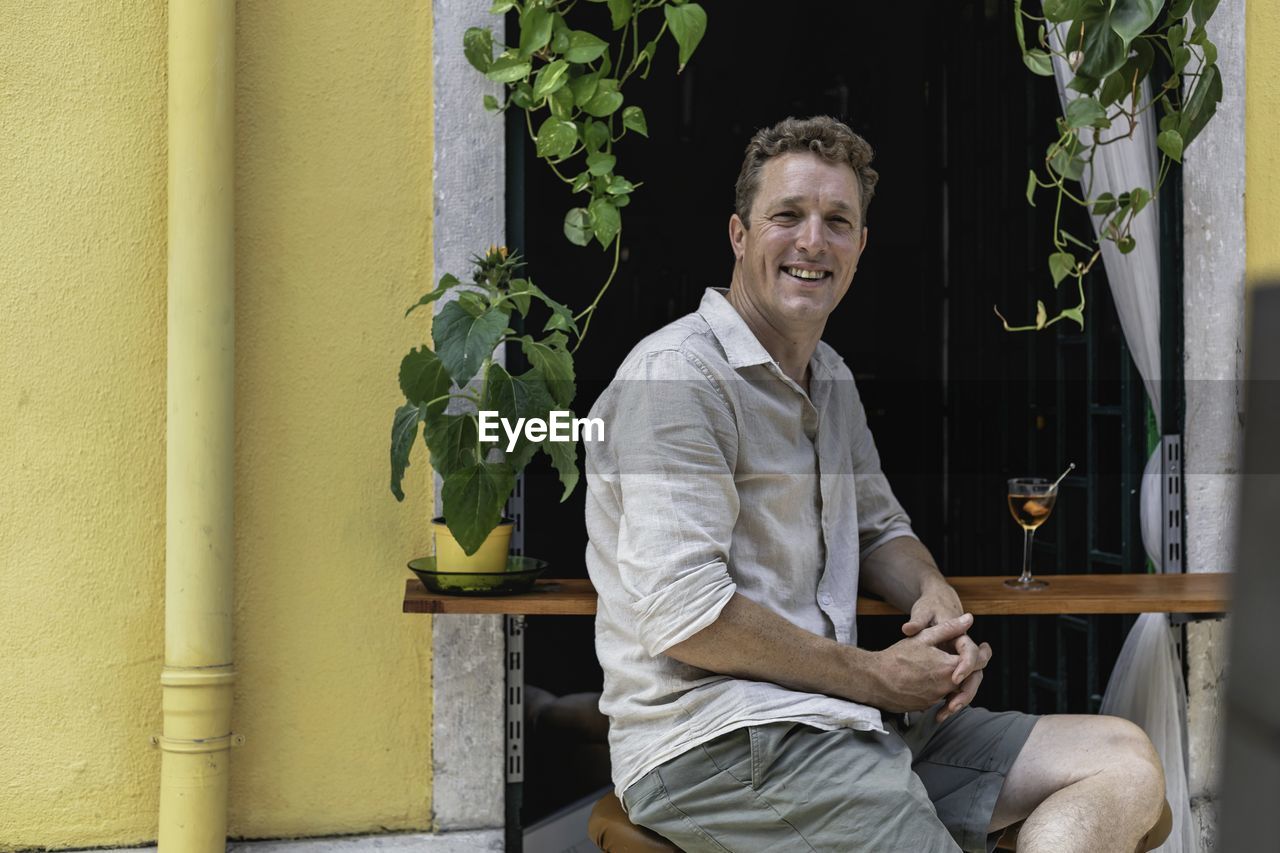 PORTRAIT OF HAPPY MAN SITTING OUTDOORS