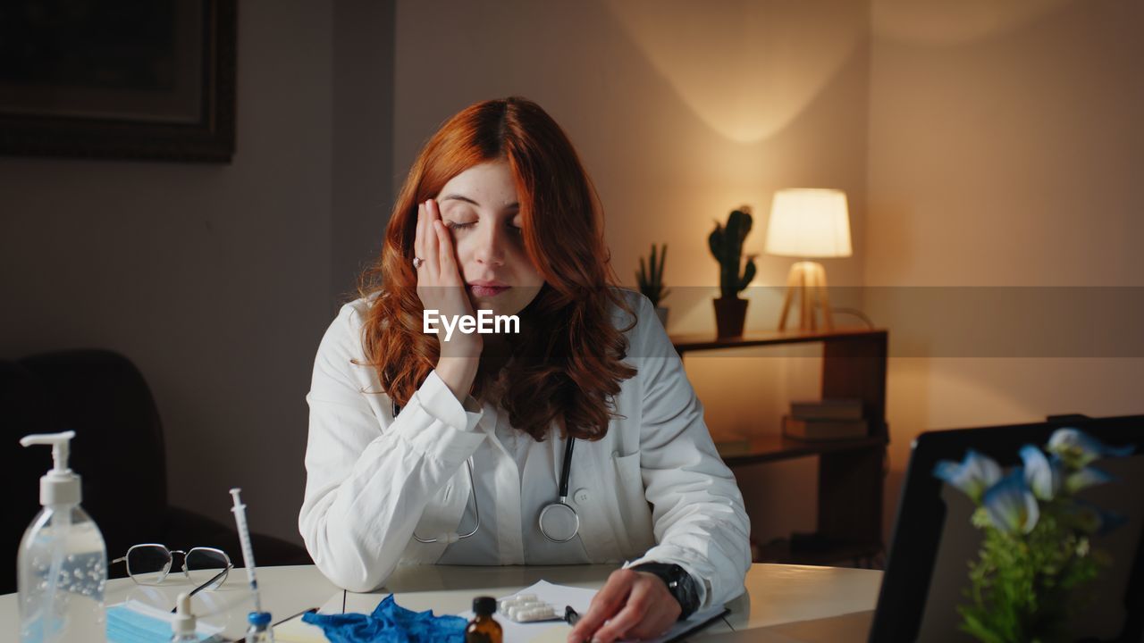 Young female doctor sleeps on the hospital desk tired of the shift