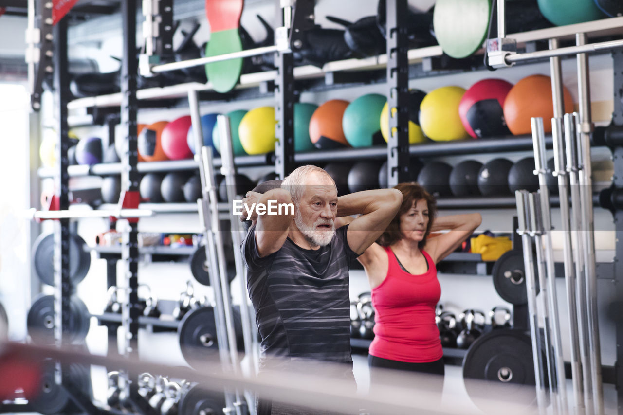 Senior mand and woman in gym exercising with medicine balls