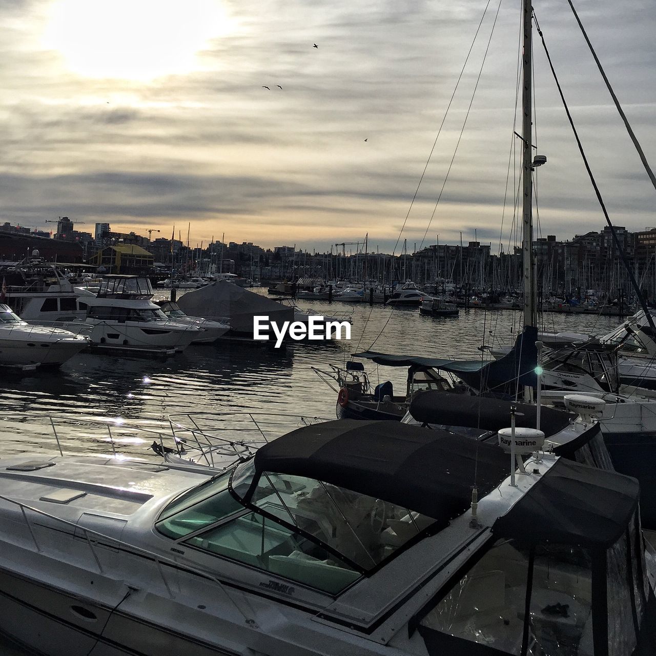 SAILBOATS MOORED ON HARBOR AGAINST SKY