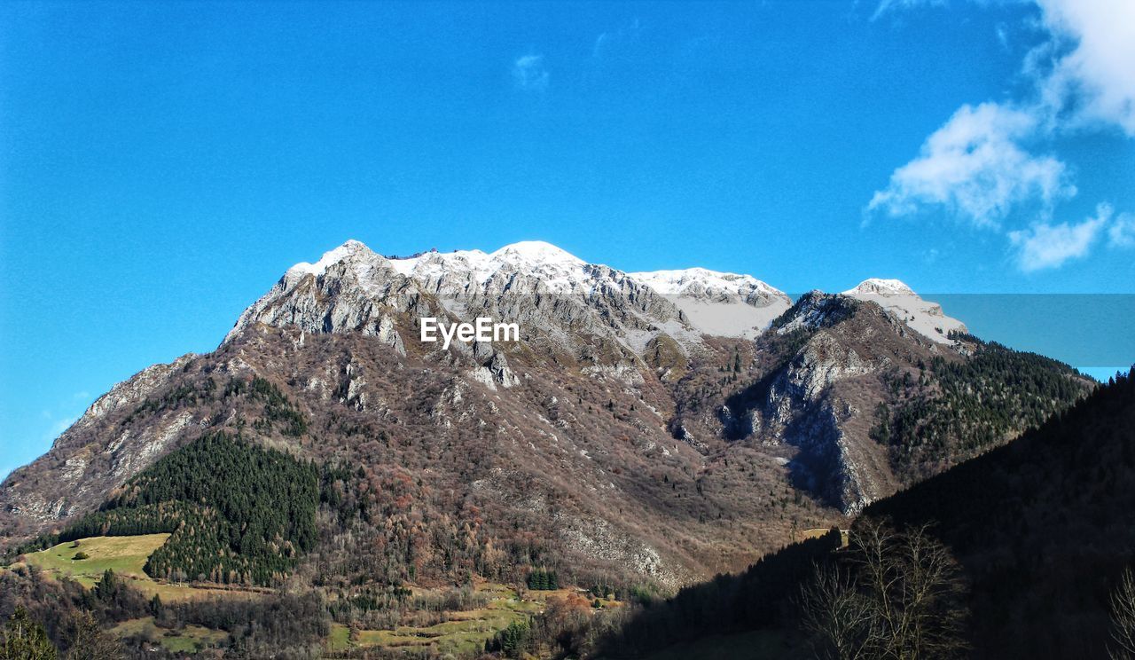 Low angle view of snowcapped mountain against blue sky