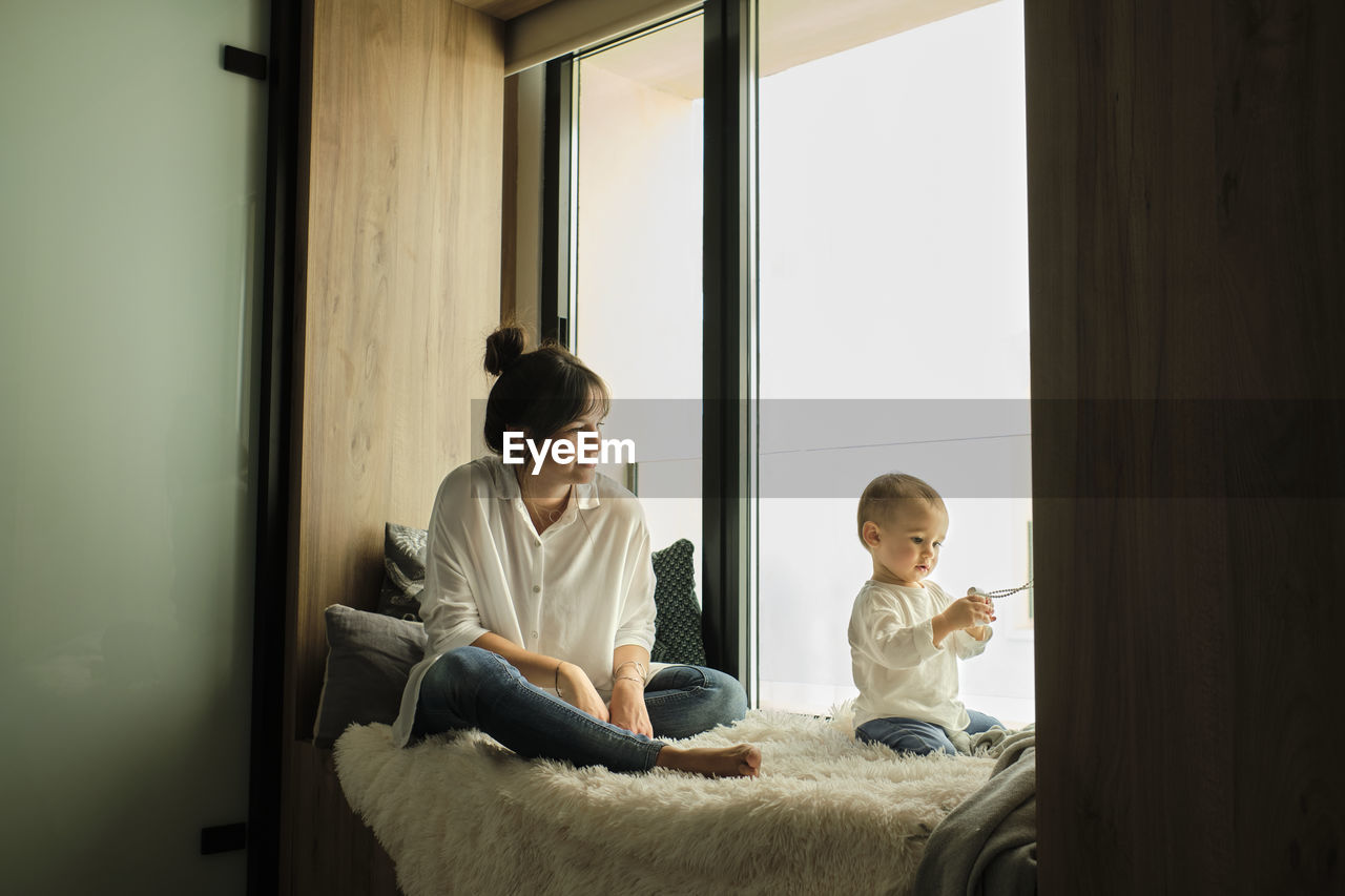 Mother sitting at the window with baby daughter