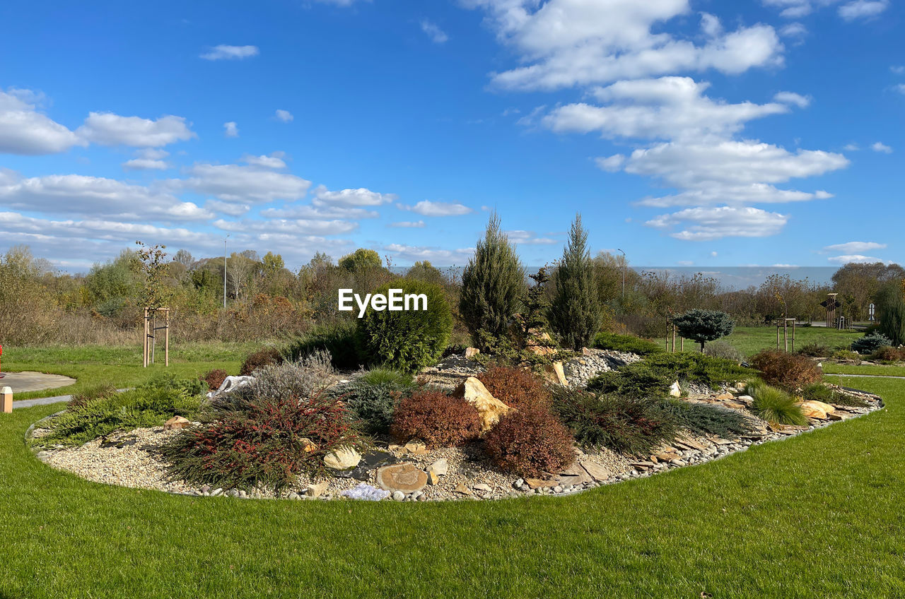 plant, sky, grass, nature, tree, landscape, cloud, environment, no people, scenics - nature, beauty in nature, lawn, green, land, garden, day, tranquility, estate, outdoors, blue, flower, field, tranquil scene, hill, architecture, non-urban scene, meadow, growth, sunlight, front or back yard