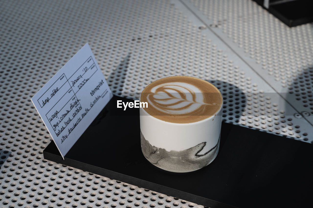 HIGH ANGLE VIEW OF COFFEE CUP ON TABLE WITH TEXT