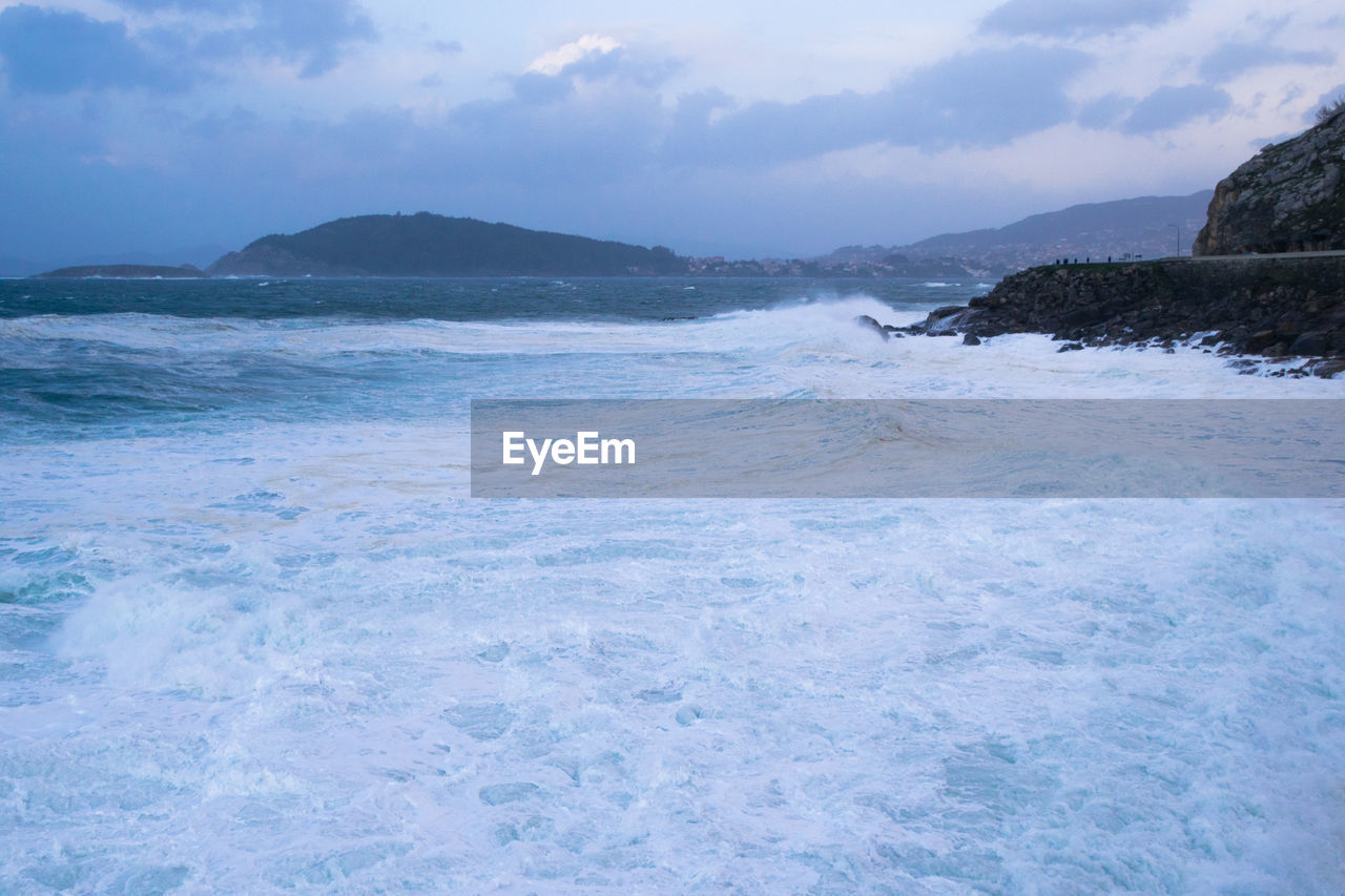 View of the waves crashing against the coastline in baiona on a stormy day