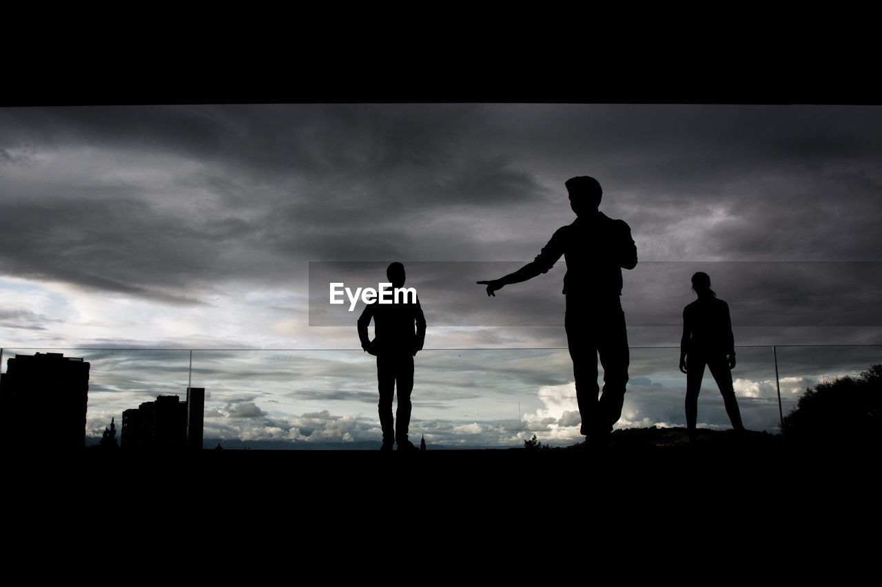 SILHOUETTE PEOPLE ON SOCCER FIELD AGAINST SKY DURING SUNSET