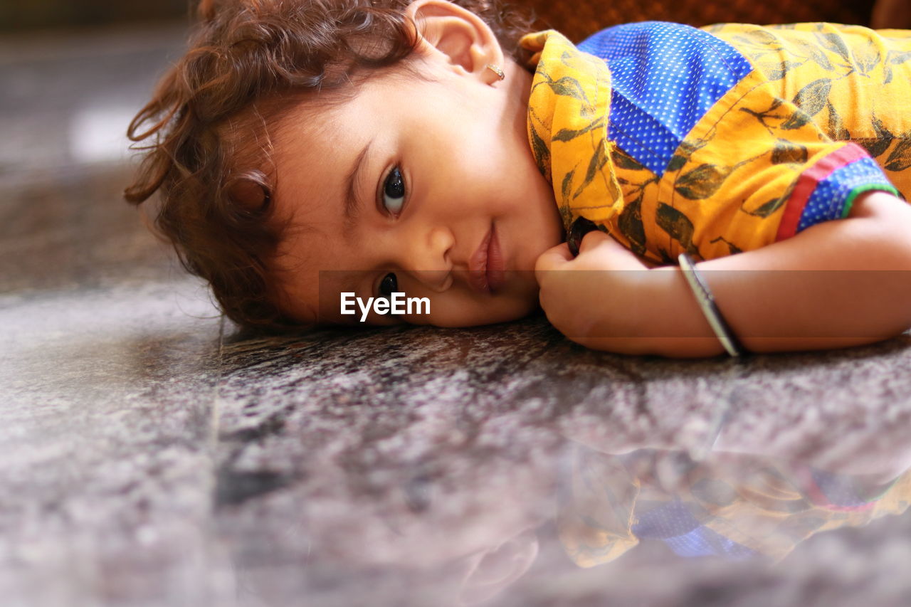 A child looking at the camera on the black marble floor