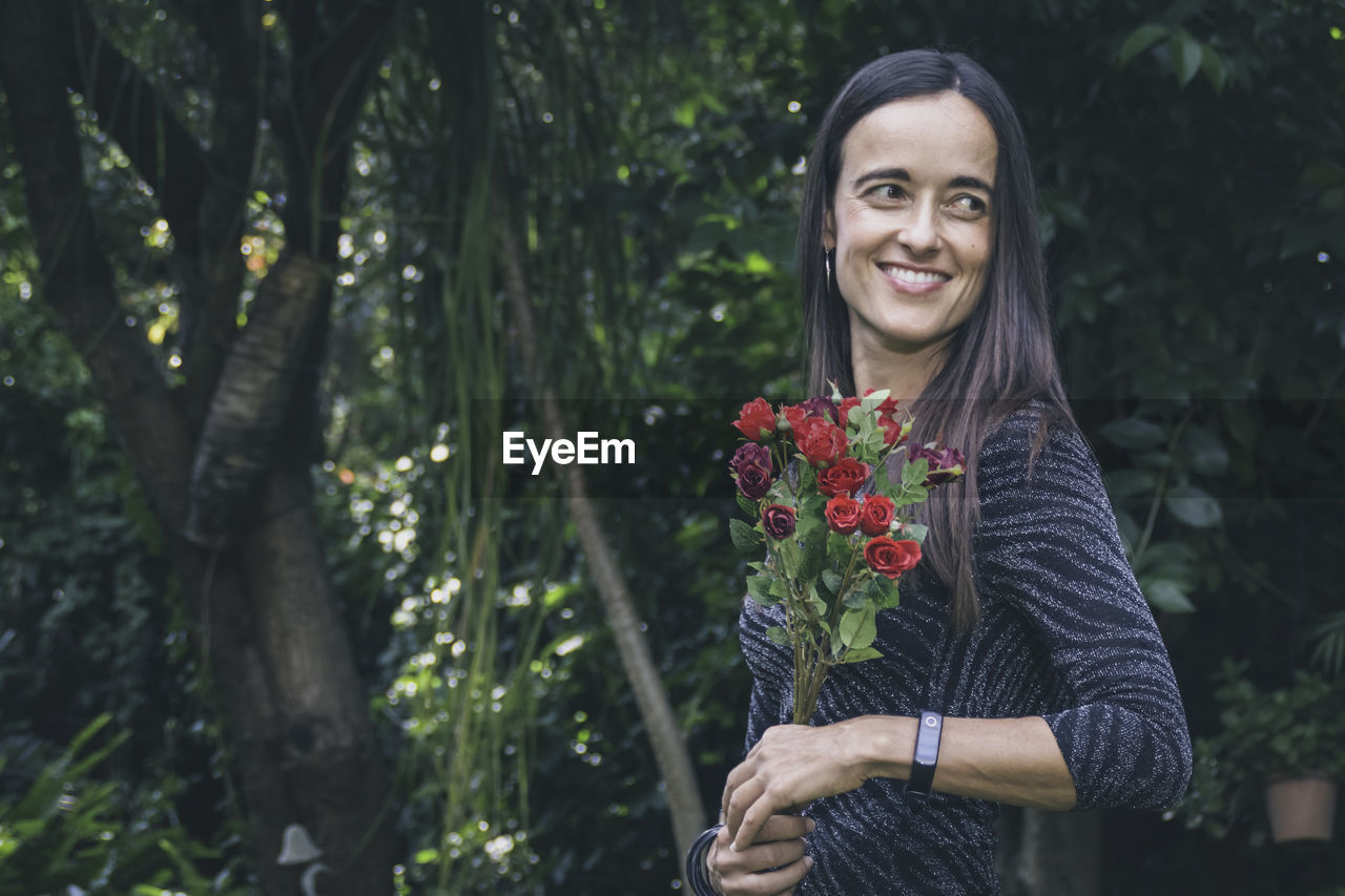 Beautiful woman posing in her garden., while holding flowers