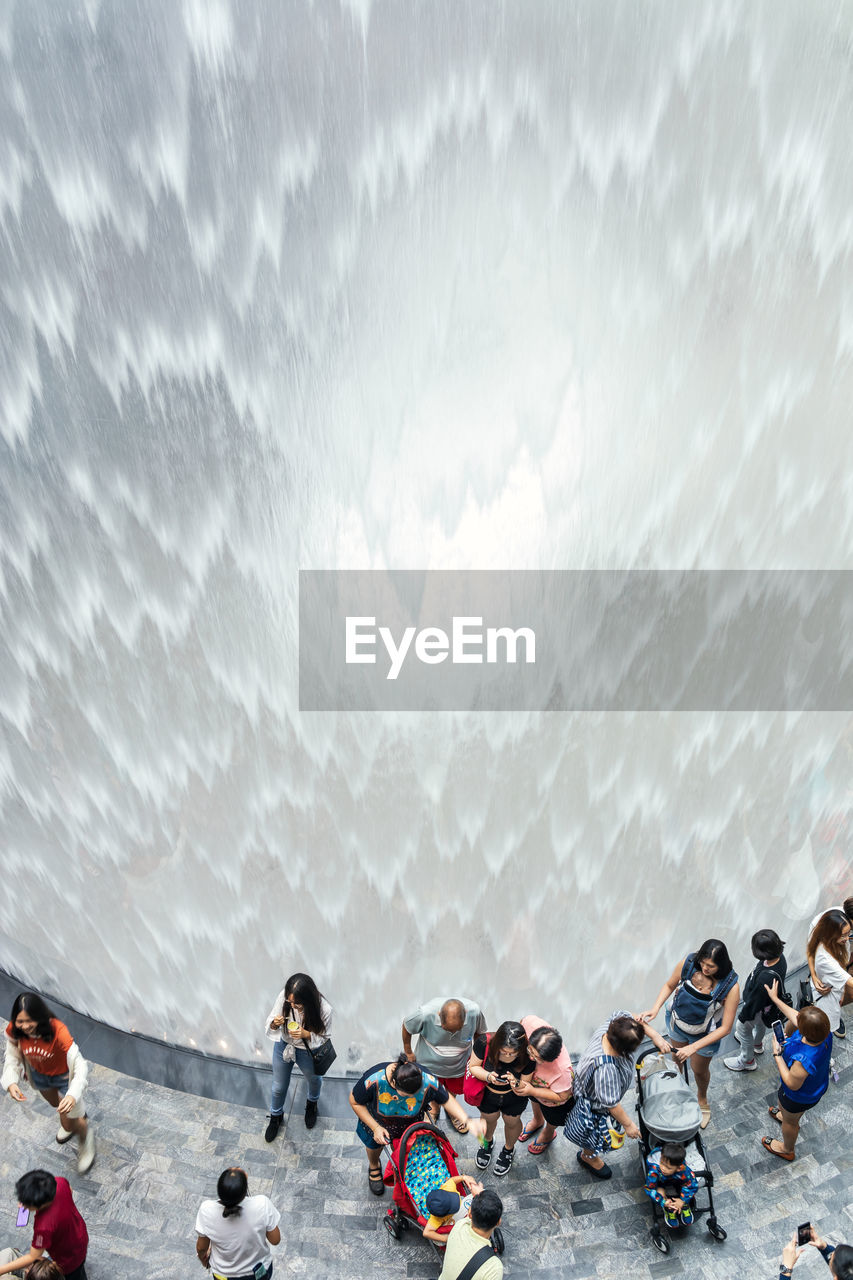 Tourists visit the hsbc rain vortex, world's largest indoor waterfall at in jewel changi airport