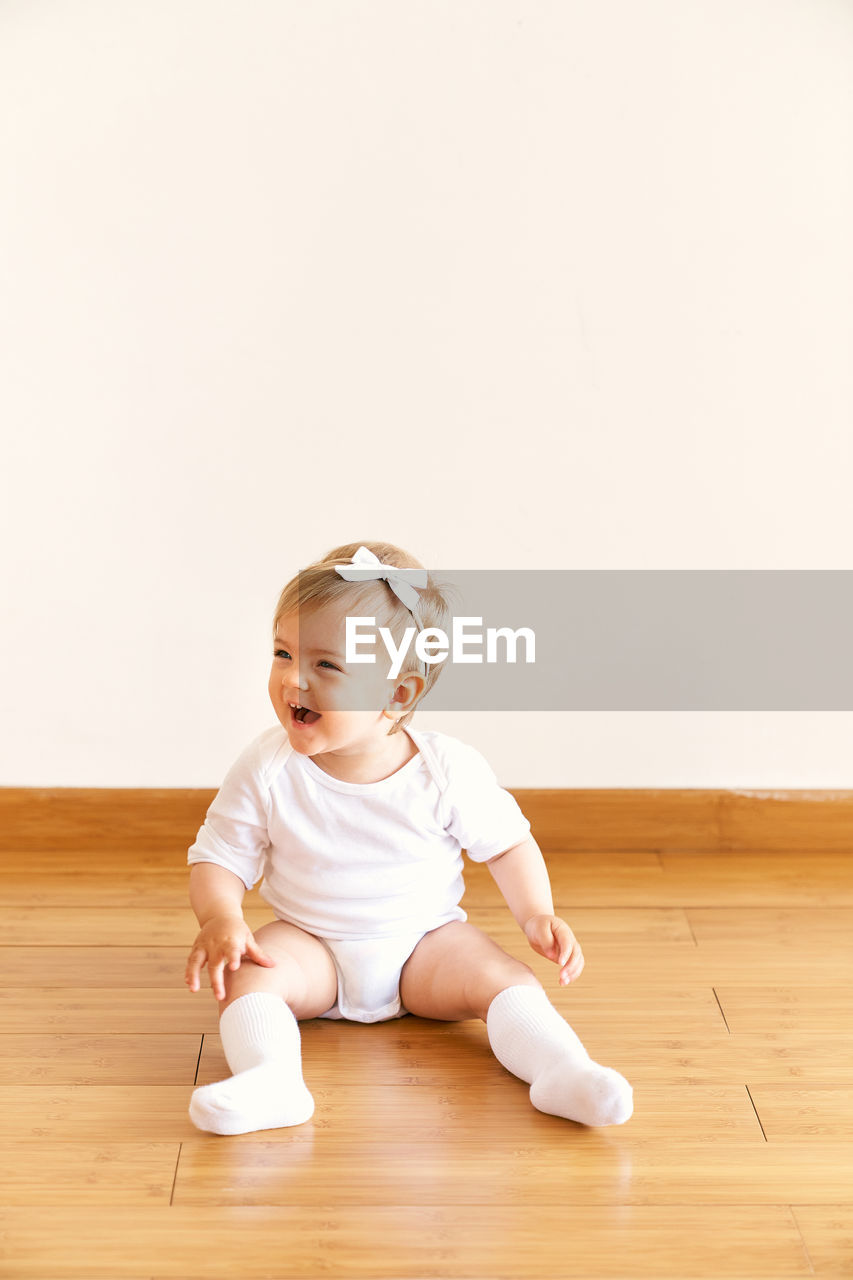 Cute baby girl on hardwood floor at home