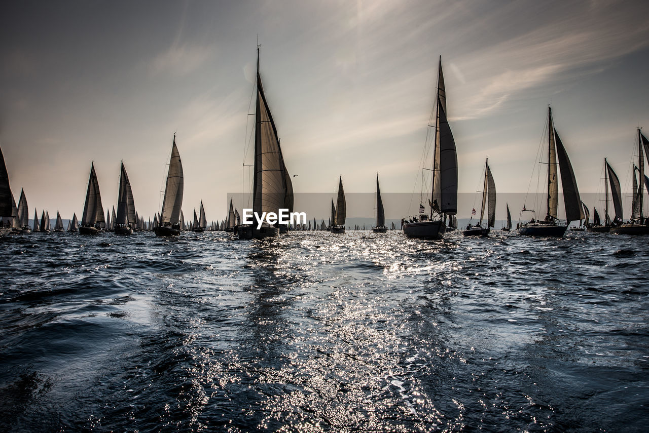 Sailboats sailing in sea against sky