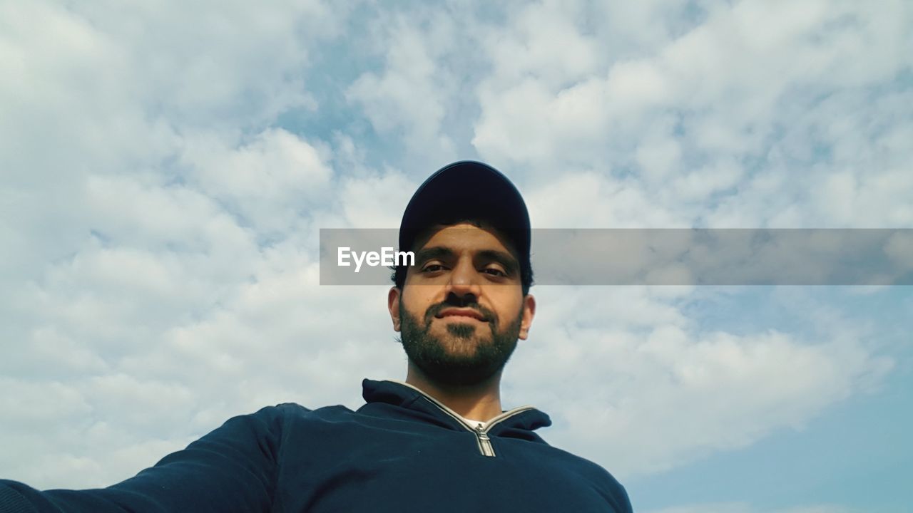 Low angle view of man standing against cloudy sky