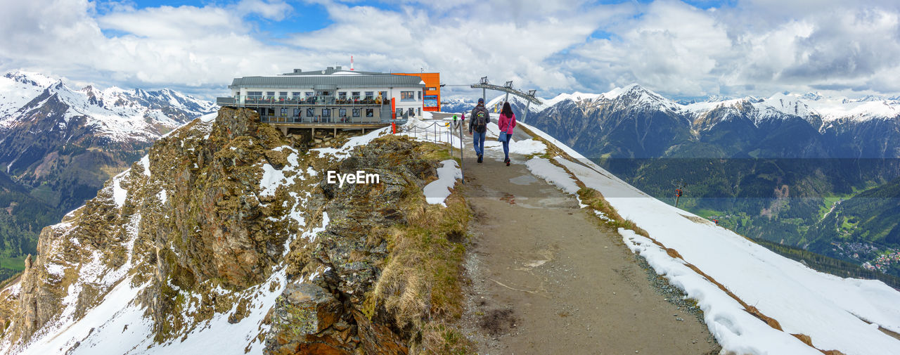 REAR VIEW OF MAN ON SNOWCAPPED MOUNTAIN