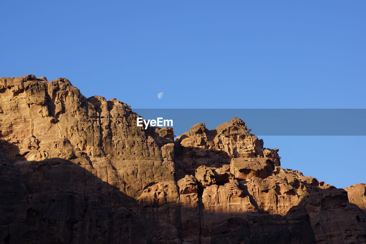 Low angle view of rock formations against clear blue sky