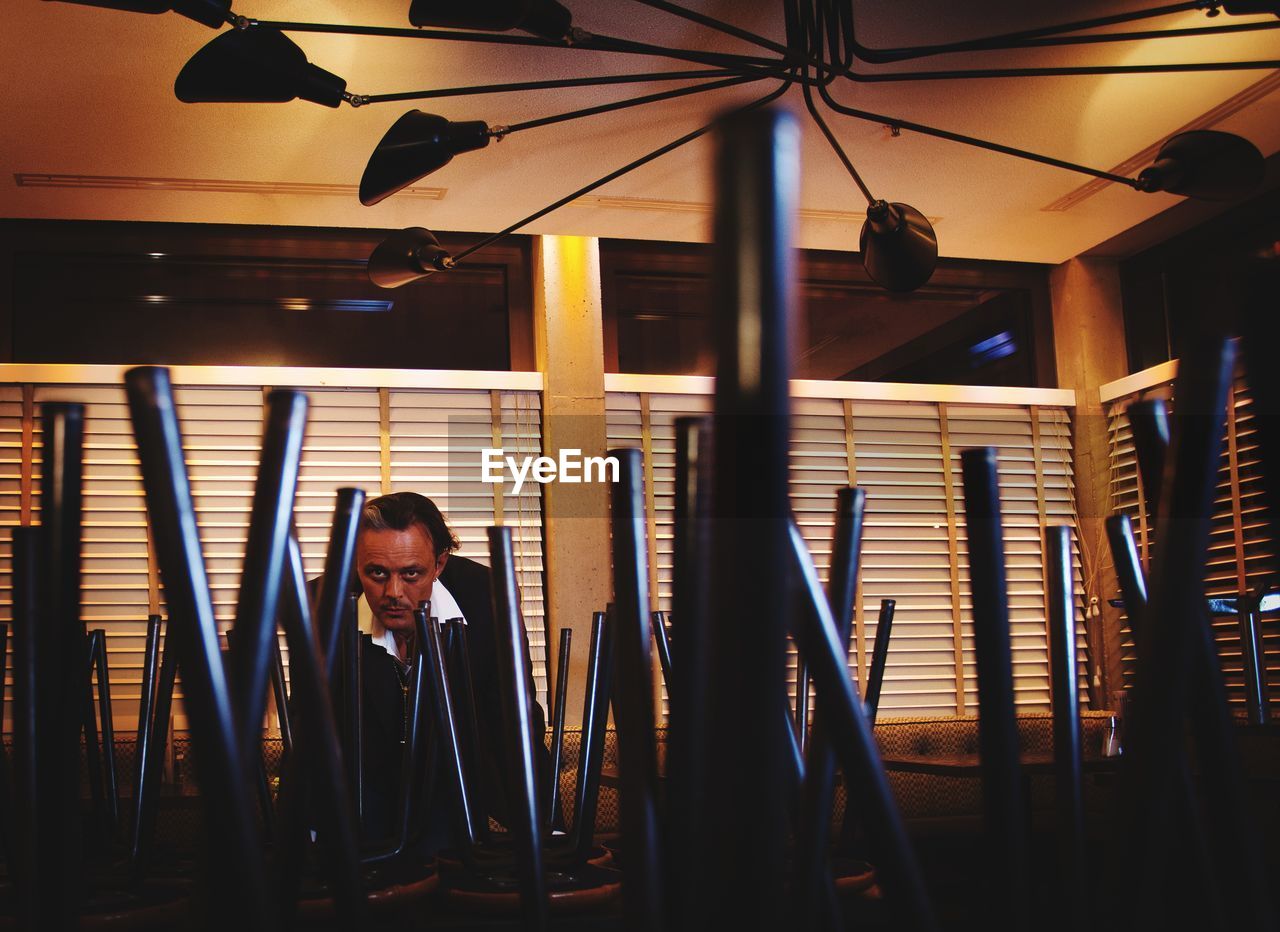 Man seen through upside down stools in restaurant