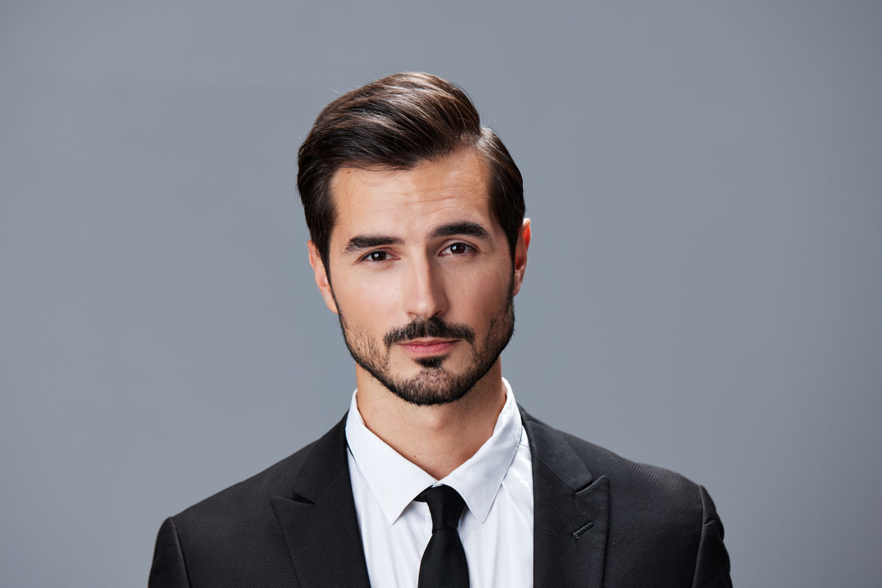 close-up portrait of young man against gray background