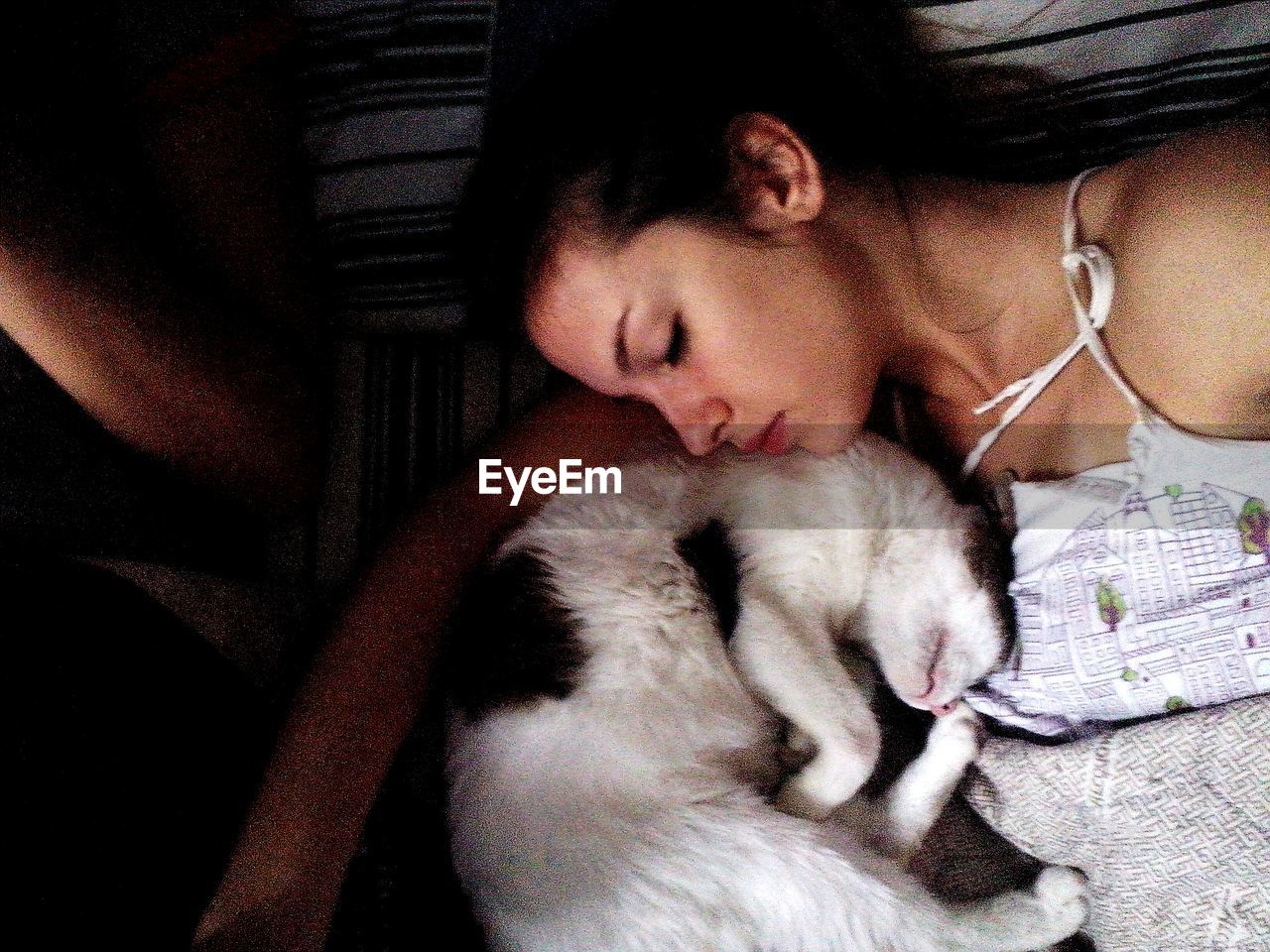 Woman with cat sleeping indoors