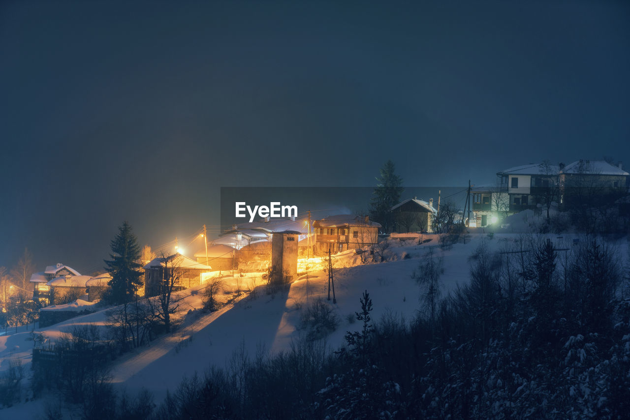 Houses and trees against clear sky during night