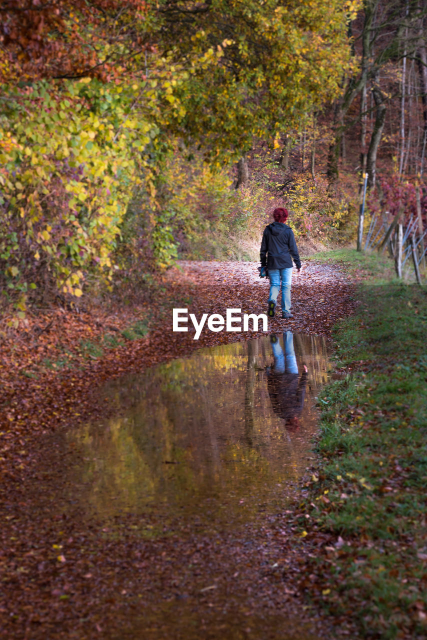 Full length of woman walking in forest during autumn